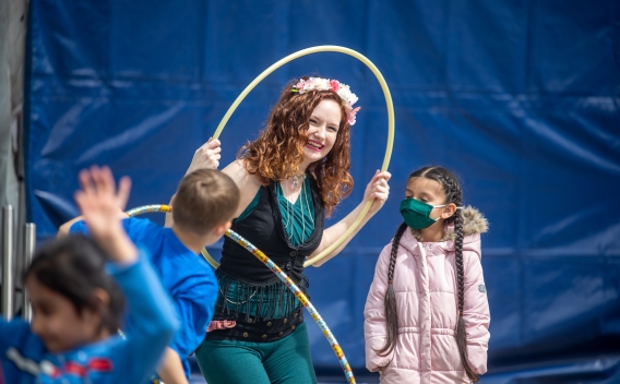 Women leads group of children in playing with hula hoops